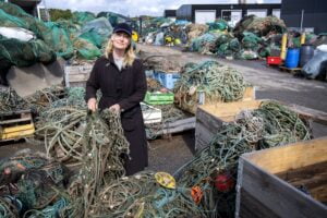 Maria Pettersson, projektledare för den marina återvinningscentralen. står ute omgiven av backar med skräp från havet.