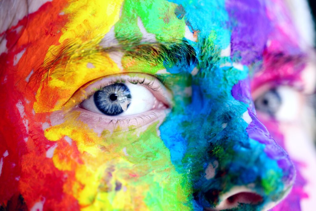 Närbild på ett ansikte som är målat i flera olika färger