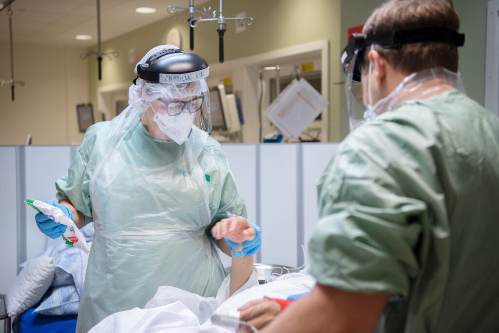 Två vårdpersonal står vid en sjukhussäng.