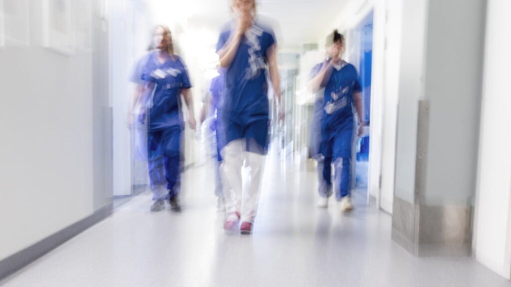 Bild på vårdpersonal som går i en sjukhuskorridor.
