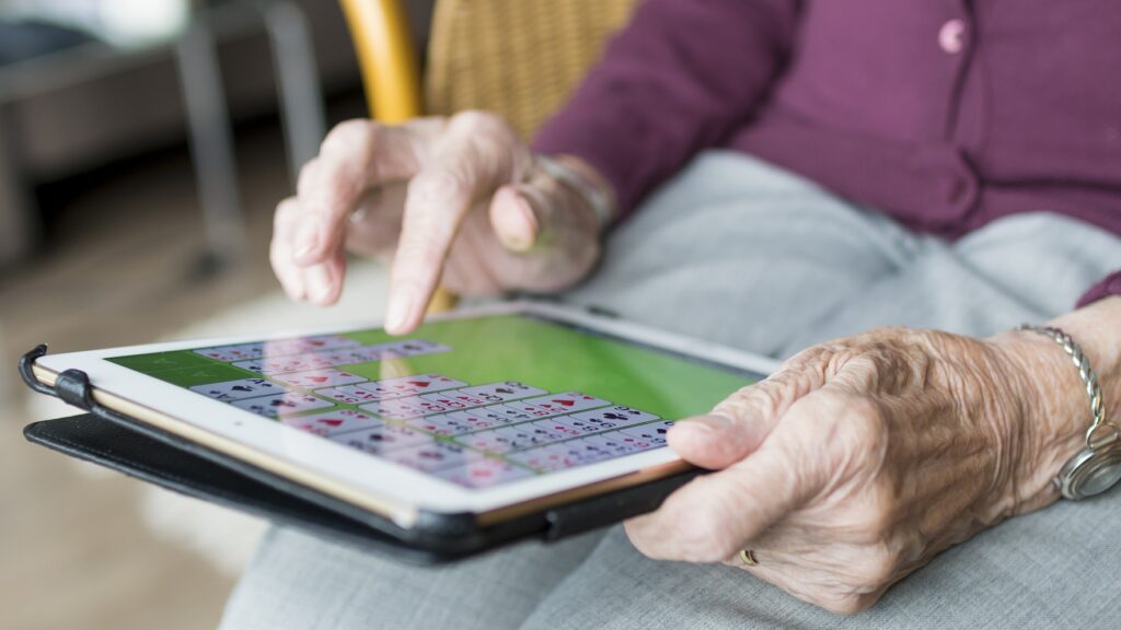 En surfplatta som hålls av ett par äldre händer