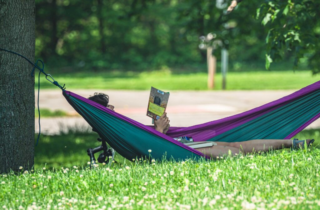 En person ligger i en hängmatta och läser en bok