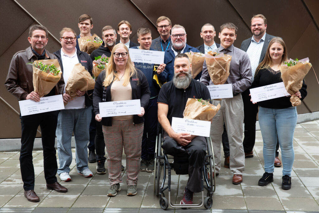 Flera personer i en gruppbild. De har blommor i handen och prischeckar.