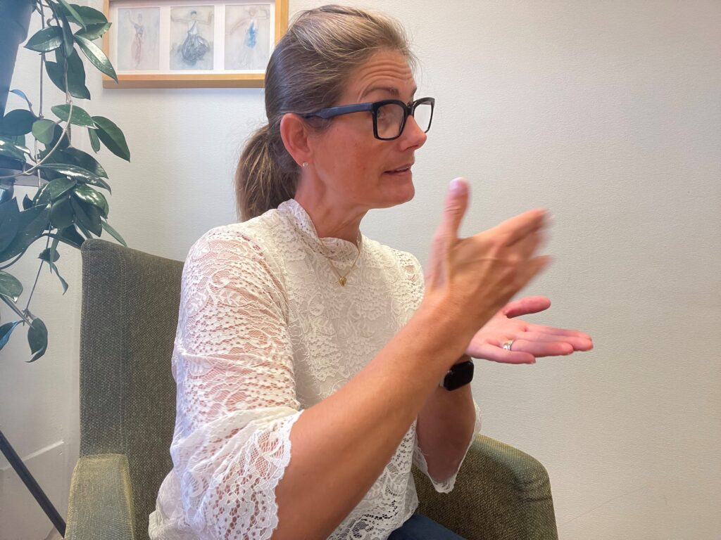 Kvinna som sitter och gör tolkrörelser med händerna.