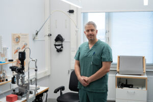 Man klädd i läkarkläder står i ett undersökningsrum.