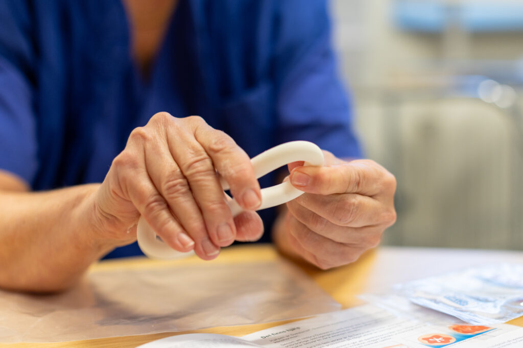 Två händer som håller i en prolapsring.