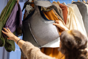 En kvinna som "bläddrar" bland klädesplagg som är upphängda på en stång.