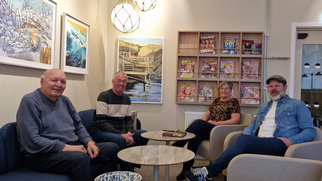 Fyra personer sitter i en soffa och fåtöljer i ett rum som bland annat är bibliotek.