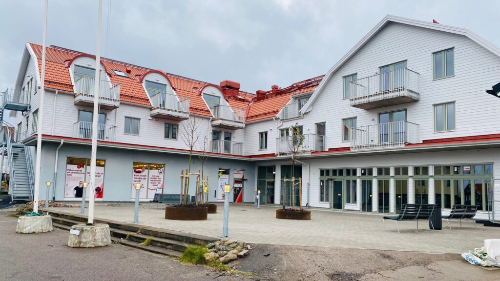 En stor vit vinkelbyggnad i trä som bland annat innehåller en matbutik.