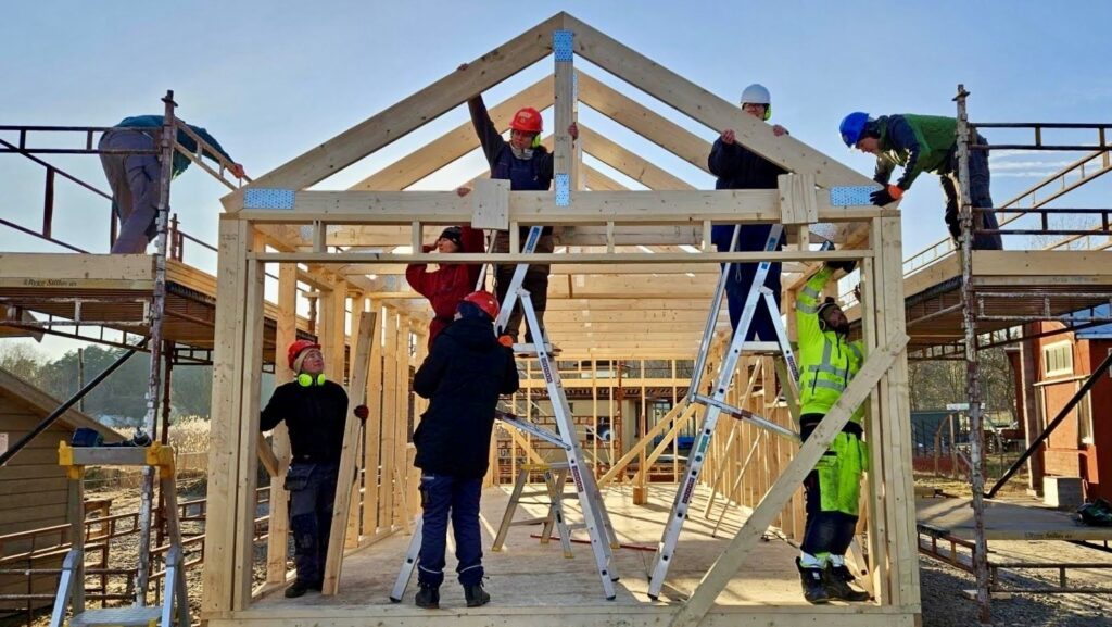Ett antal personer bygger stommen till ett hus