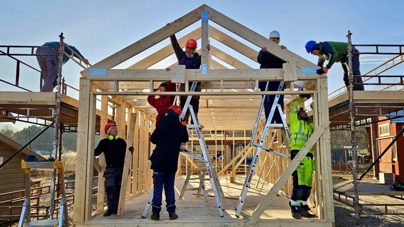 Ett antal personer bygger stommen till ett hus