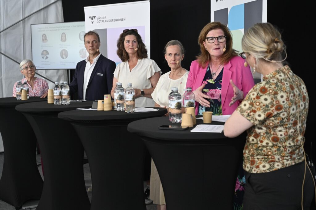 Personer som står vid bord och diskuterar.