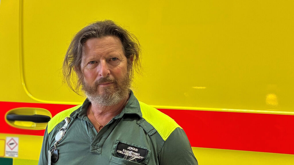 En man står framför en ambulans.
