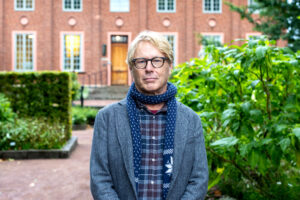 En man står utomhus. Bakom honom syns en tegelbyggnad.